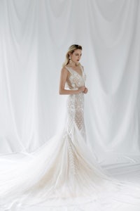 a bride in a mermaid wedding dress posing in front of a white backdrop